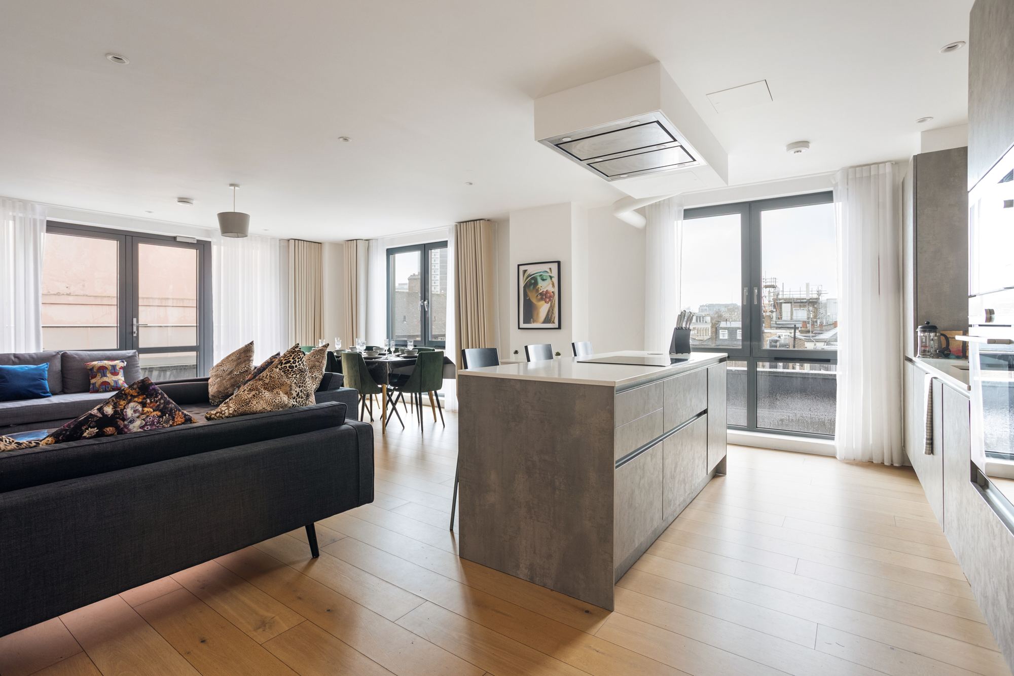Open-plan living room, dining table and kitchen island with rooftop views